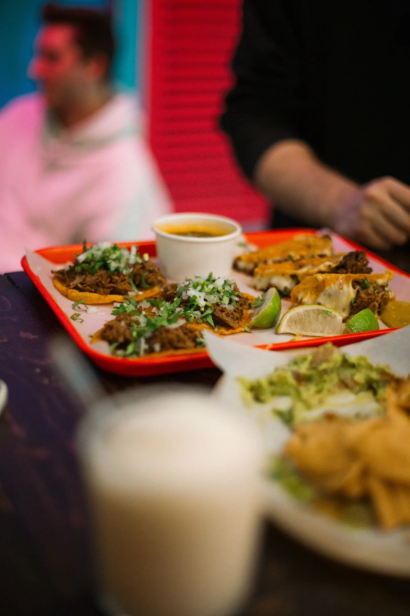 Tacos and quesabirria on a red tray in the dining room